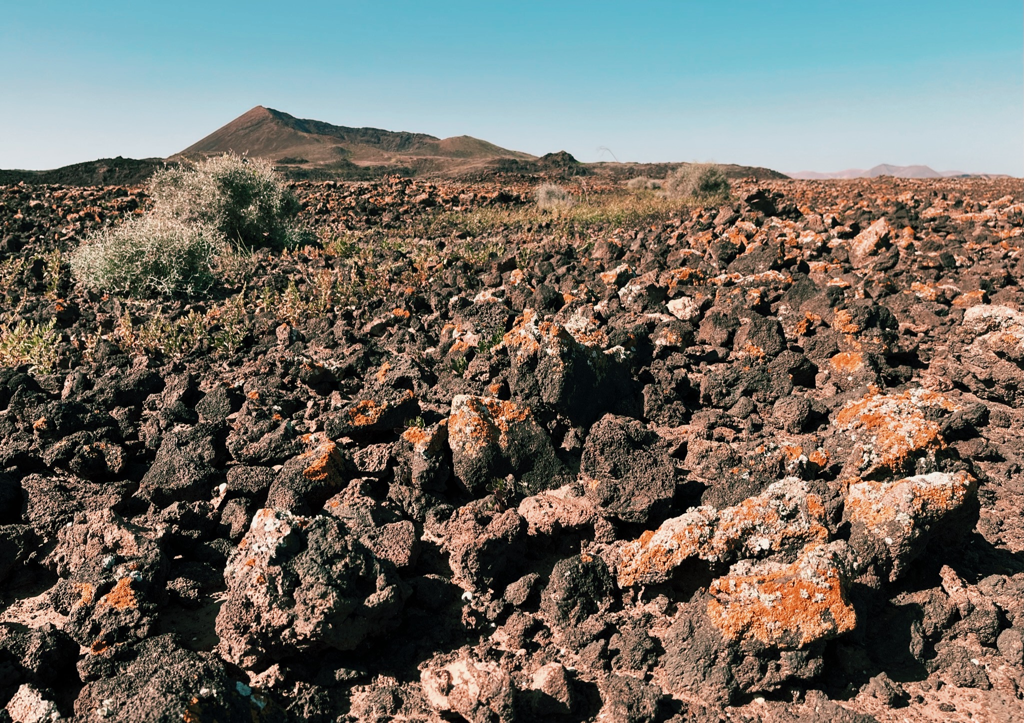 Lots of volcanic stones and gravel in hues of brown and orange leading to Caldera Los Arrabales, a hiking route on Fuerteventura