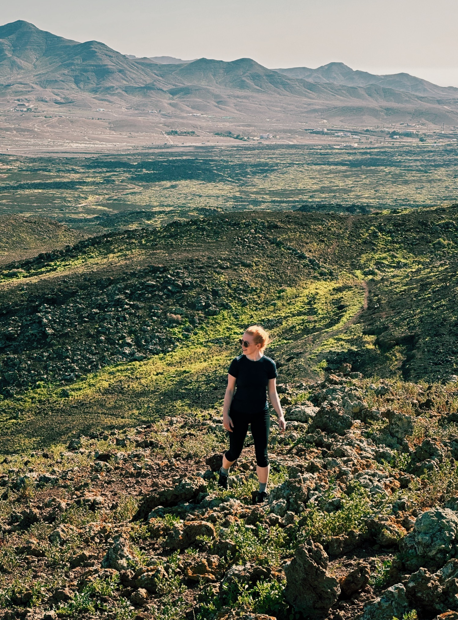 Woman walking in volcano desert in green hues at Caldera Los Arrabales, a hiking route on Fuerteventura, Spain